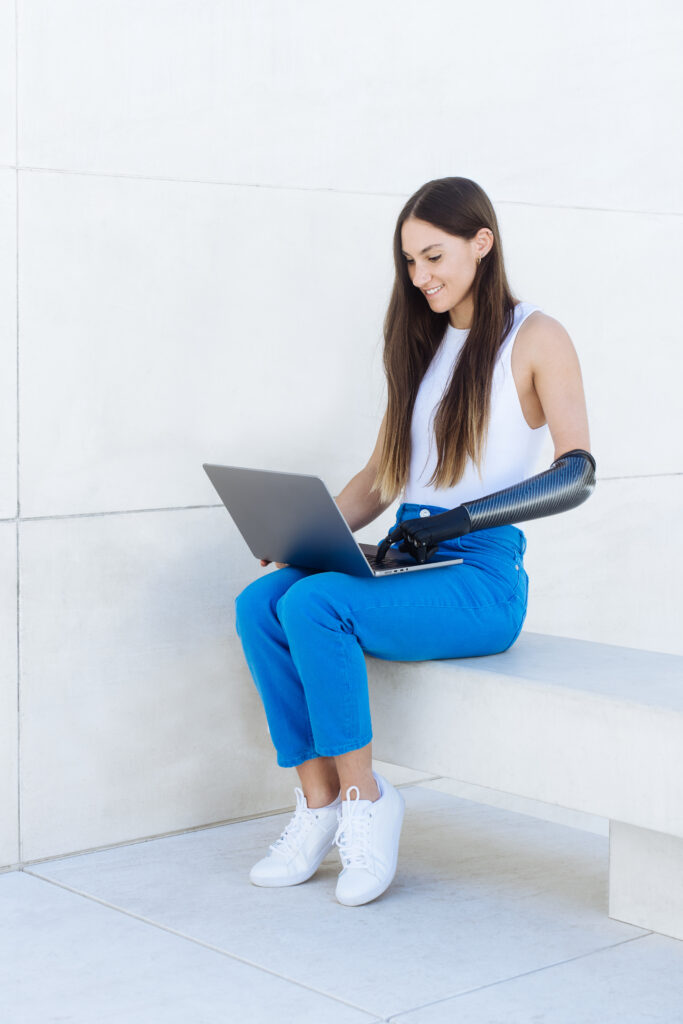 Woman with an upper limb prosthesis working on a laptop