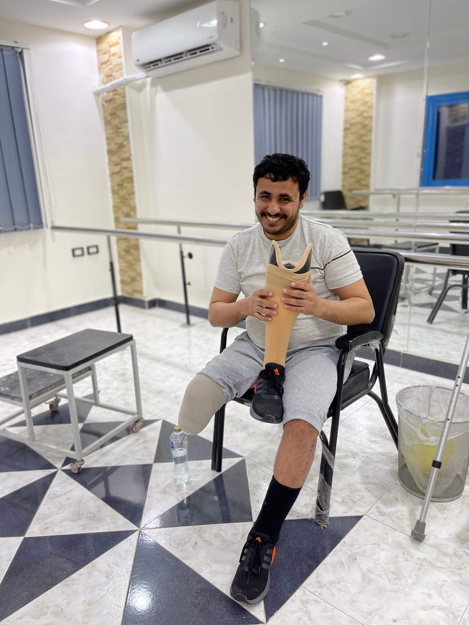 Smiling patient holding his new custom prosthetic leg at Qudra center in Cairo